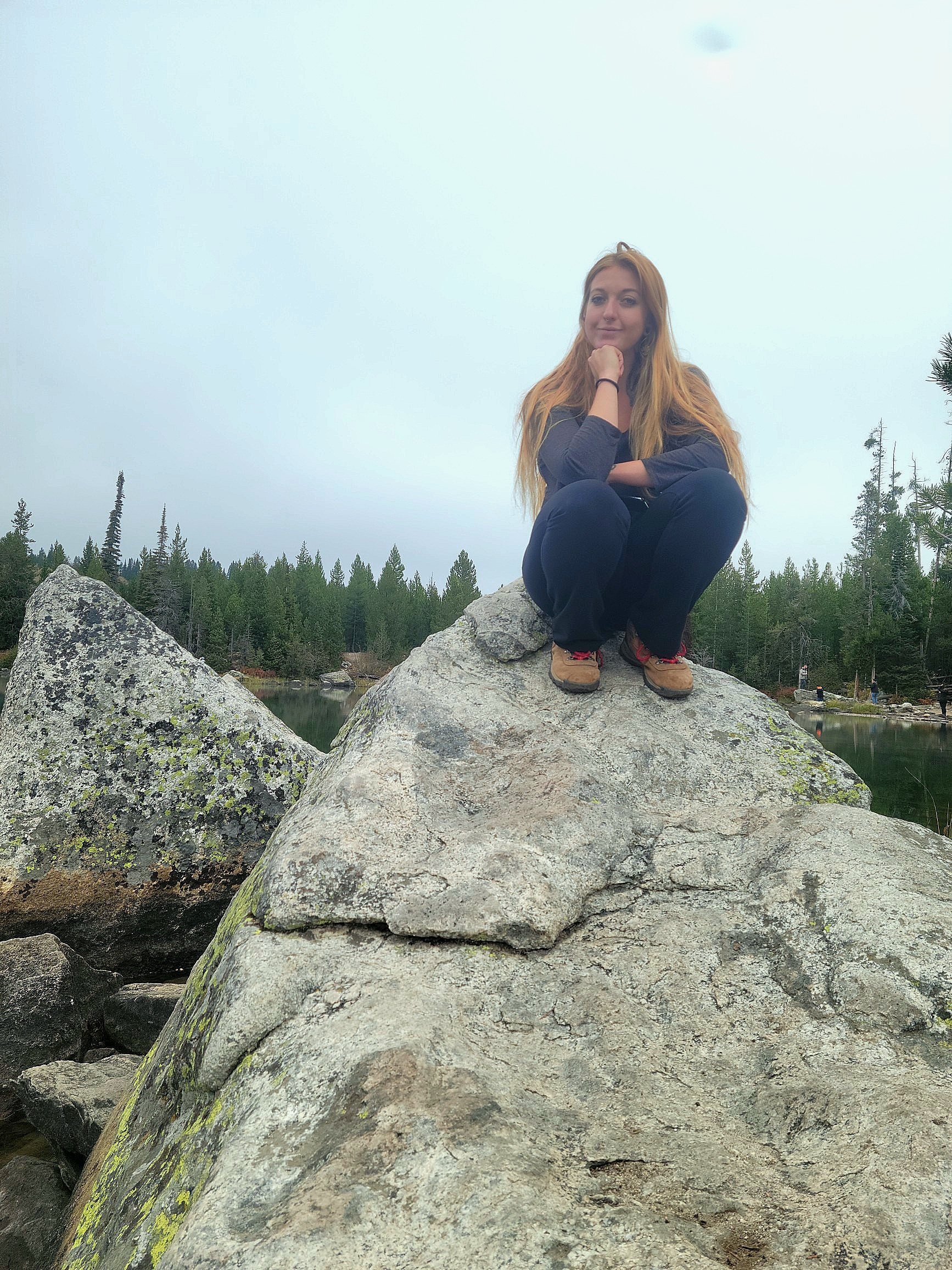 Faith sits on a rock by a lake in Grand Teton National Park